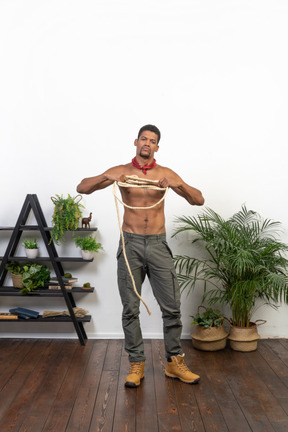 Front view of young man pulling a coil of rope apart and looking at camera