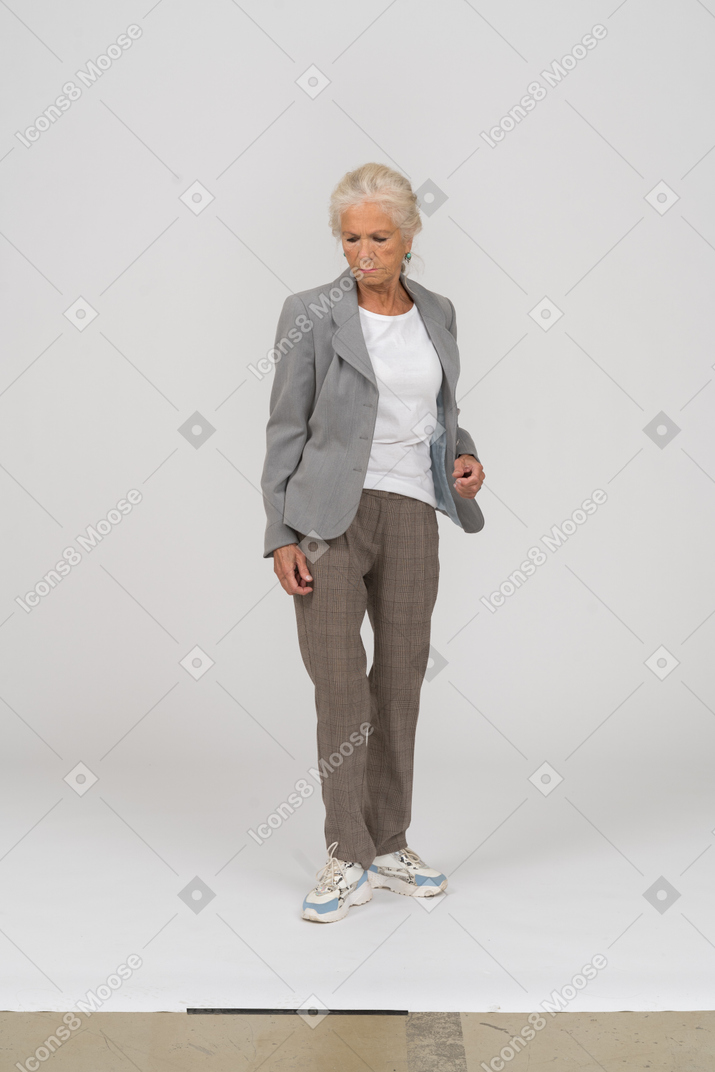 Вид спереди пожилой женщины в костюме, смотрящей вниз