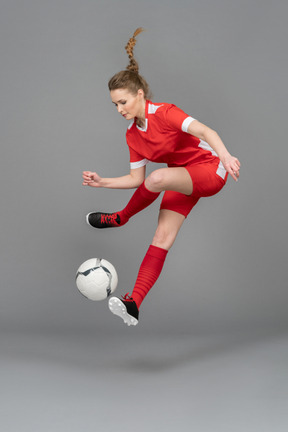 A sporty young woman jumping with ball