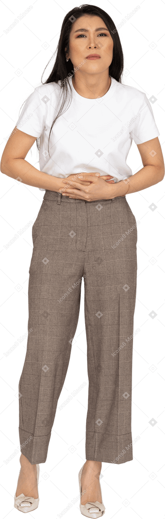 Vista frontal de uma jovem de calça e camiseta tocando a barriga