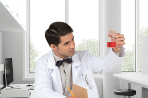A man in a lab coat holding a flask of liquid