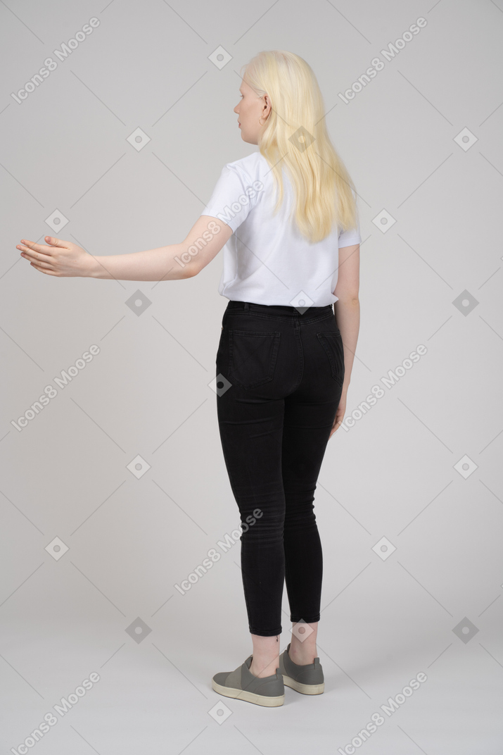 一个年轻女孩站立并举起左臂的后视图