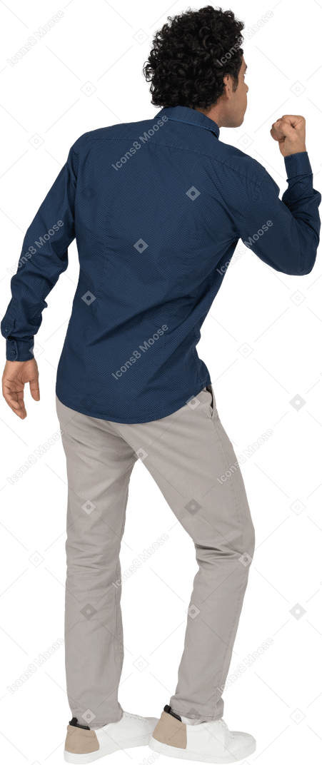 Rear view of a man in casual clothes showing fist