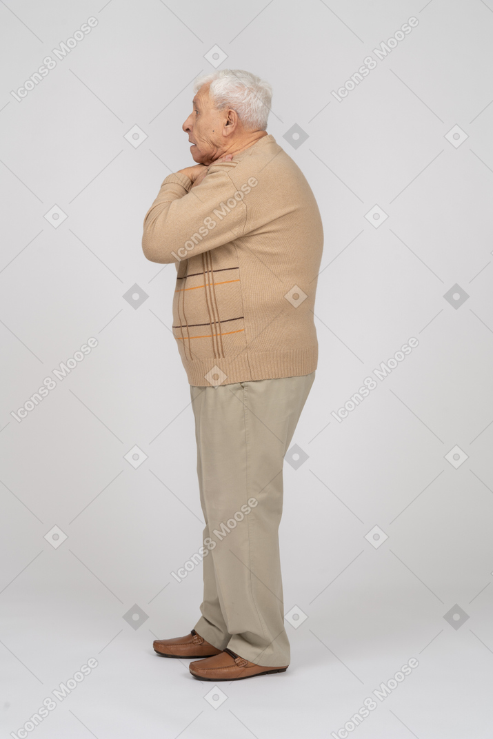 Side view of an old man in casual clothes choking himself