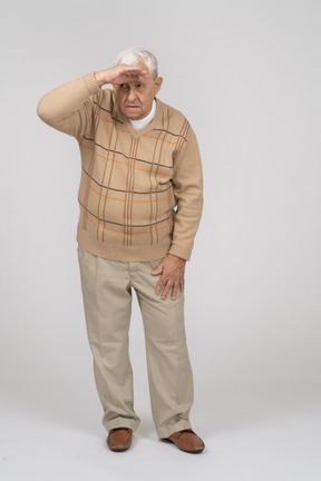 Front view of an old man in casual clothes looking for someone