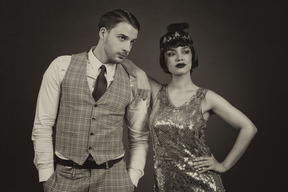 Well-dressed retro-styled couple posing in the dark