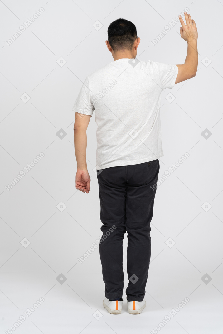 手を振っているカジュアルな服を着た男の背面図