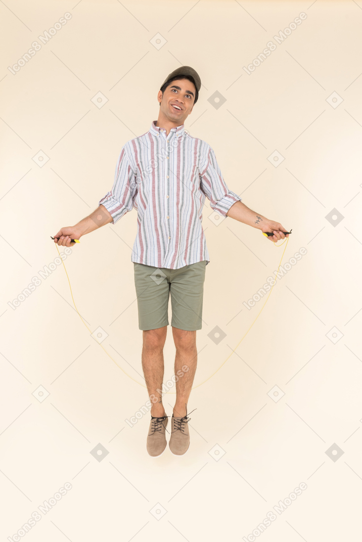 Excited looking young caucasian man jumping over jump rope
