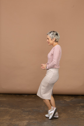 Vista lateral de uma mulher feliz em roupas casuais, posando em uma perna