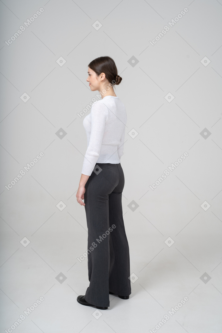 Vista di profilo di una giovane donna in maglione bianco e pantaloni neri