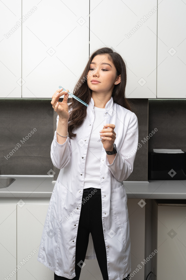 Vue de face d'une femme dentiste tenant soigneusement une brosse à dents