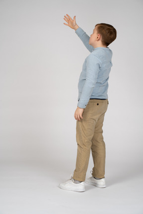 Back view of young boy lifting up his arm