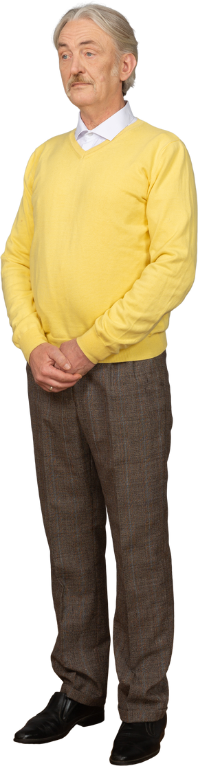 Трехчетвертный вид сбитого с толку старика, который держится за руки и носит желтый свитер