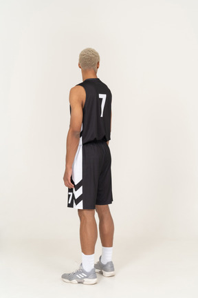 Three-quarter back view of a young male basketball player looking up