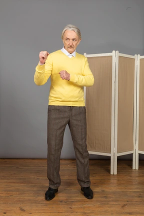 Vista frontal de un anciano apretando los puños listo para defender