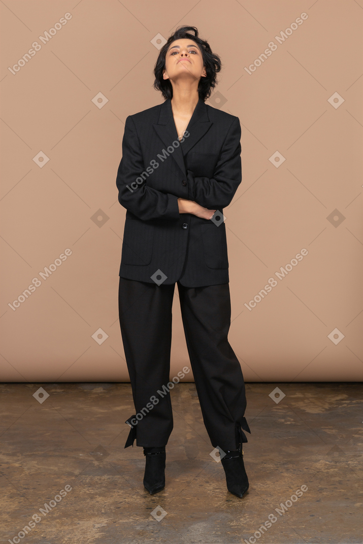 Front view of a businesswoman dressed in black suit crossing hands and throwing head back