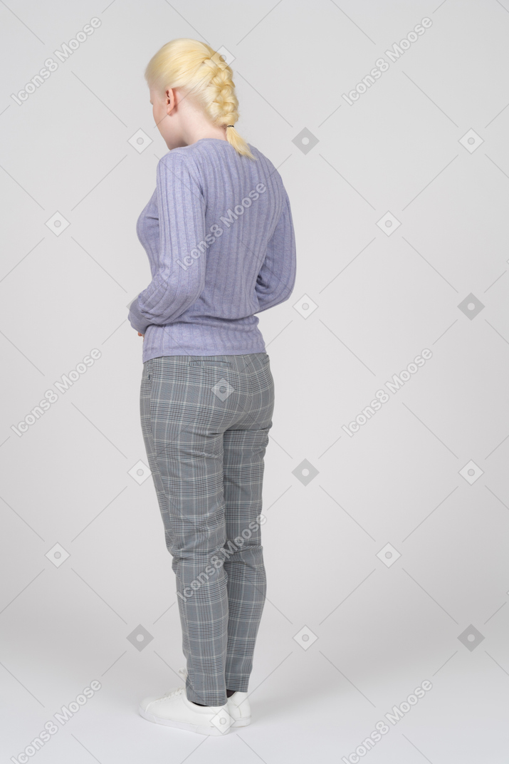Vista traseira de três quartos de uma mulher em roupas casuais, olhando para baixo