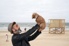 Homem olhando para seu cachorro na praia