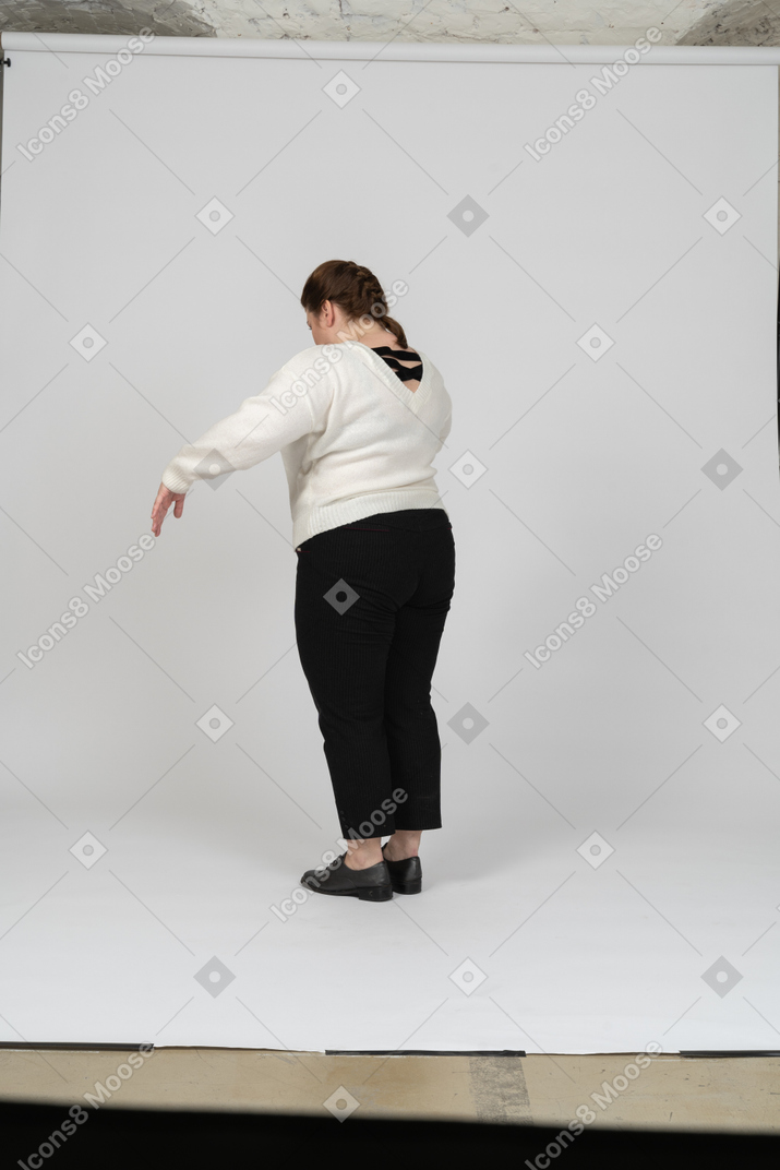Vista lateral de una mujer regordeta en suéter blanco gesticulando