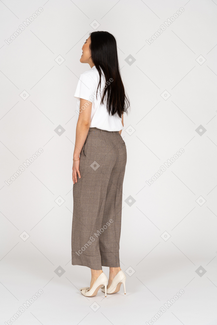 Vista posterior de tres cuartos de una joven sonriente en pantalones y camiseta