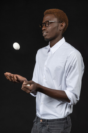 Three-quarters shot of a chef tossing up an egg in a black background