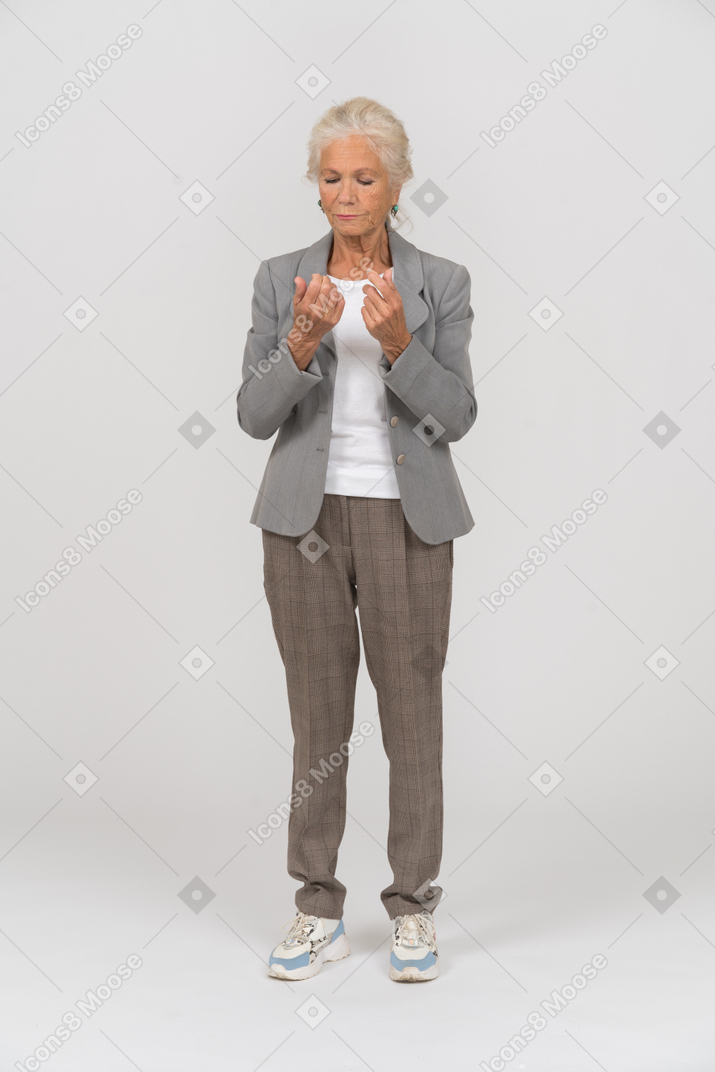 Vista frontal de una anciana en traje mirando sus uñas