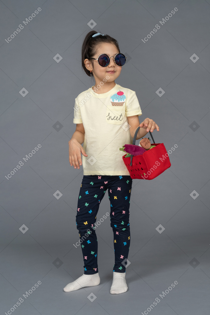 一个戴墨镜的小女孩拿着购物篮的肖像