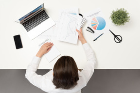 A female office worker at the table holding papers with diagrams