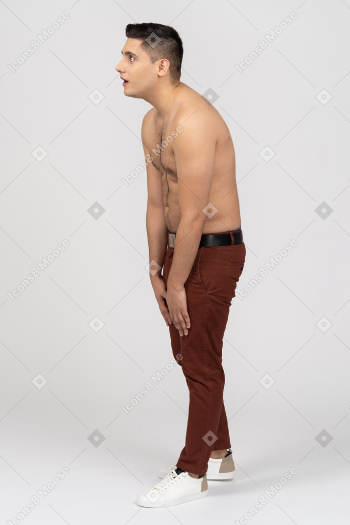 Vista lateral de un hombre latino sin camisa mirando a un lado con sorpresa