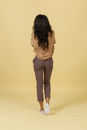 Back view of a dark-skinned young female taking off her pullover