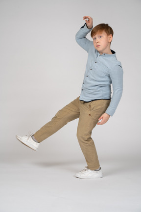 A young boy in a blue shirt balancing on one leg