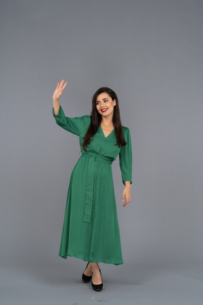 Front view of a greeting young lady in green dress