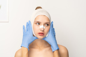 Female patient with gloved hands framing her face