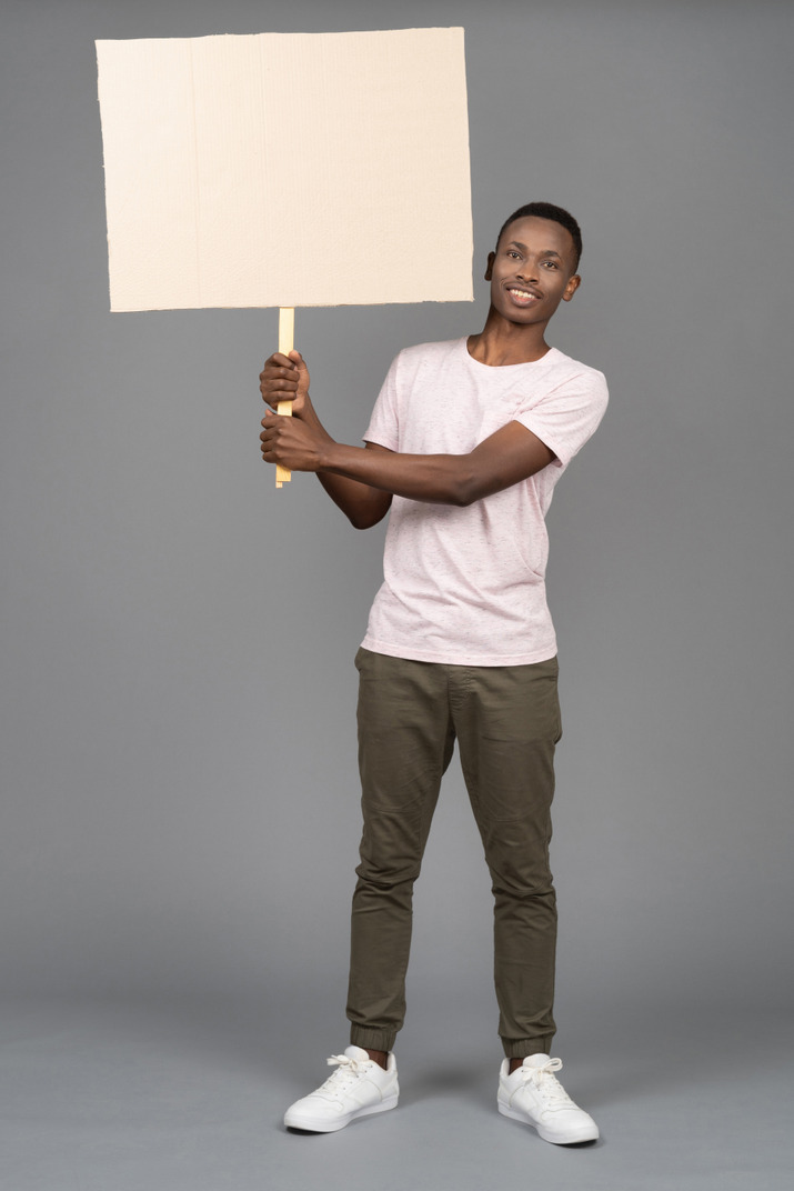 A cheerful young man holding a blank poster