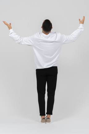Back view of young man raising his arms