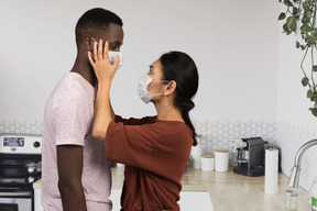 A man and a woman wearing masks in a kitchen
