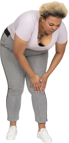 Mujer inclinada hacia adelante para tocar su rodilla lesionada
