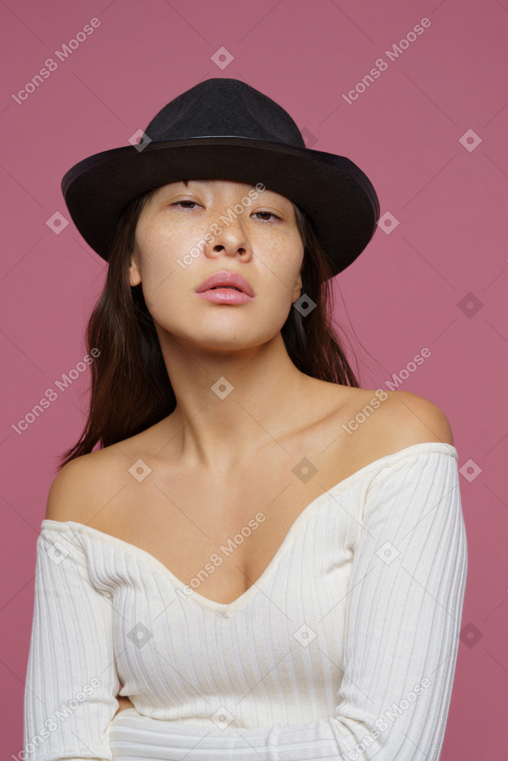 Front view of a young female in black hat judgmentally looking at camera