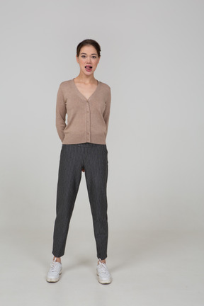 Front view of a young lady in pullover and pants showing tongue