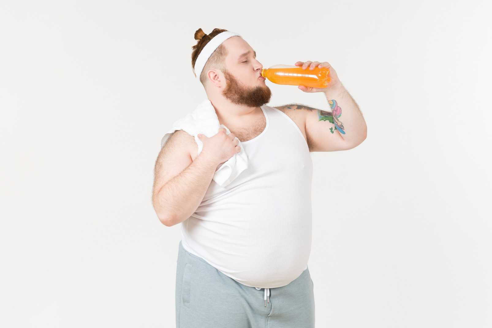 A fat man in sportswear drinking a soft drink from the bottle
