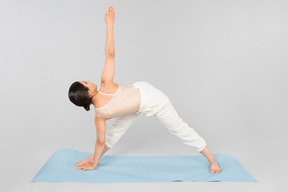 Joven mujer india de pie sobre la estera de yoga en una pose