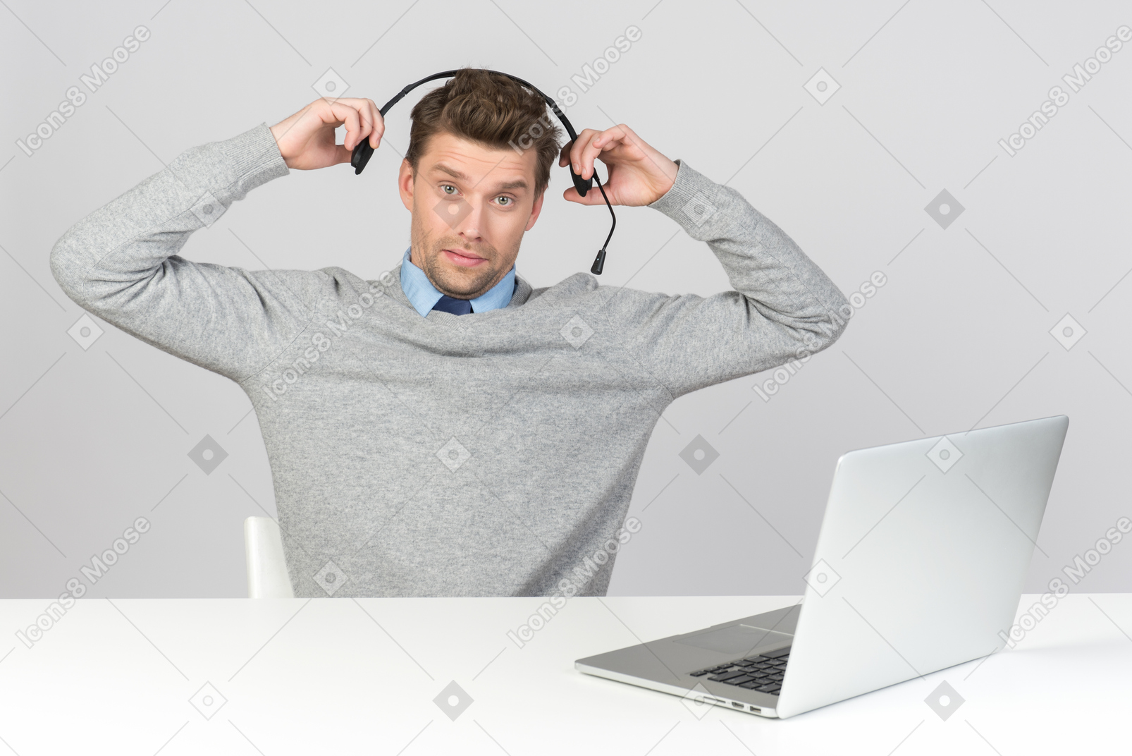 Call center agent pulling off his headset while working on computer