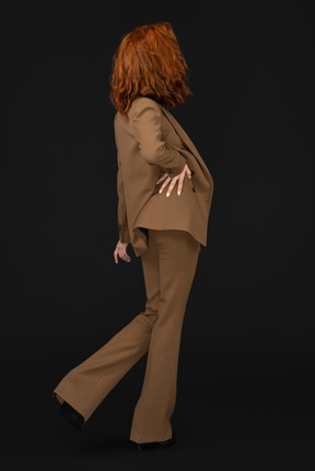 A woman with red hair wearing a tan suit