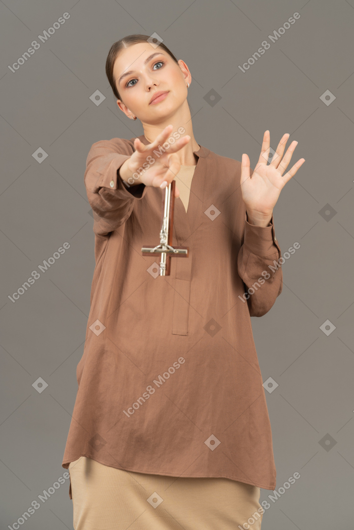 Young christian woman holding a cross upside down