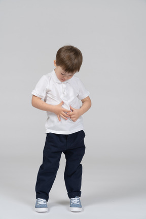 Little boy with hands on his stomach looking down