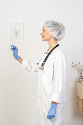 Side view of a young female doctor with stethoscope holding thermometer