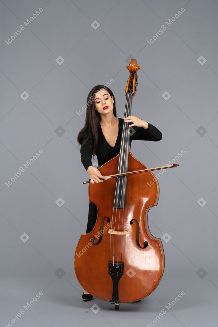 Vue de face d'une jeune femme en robe noire jouant de la contrebasse avec un arc