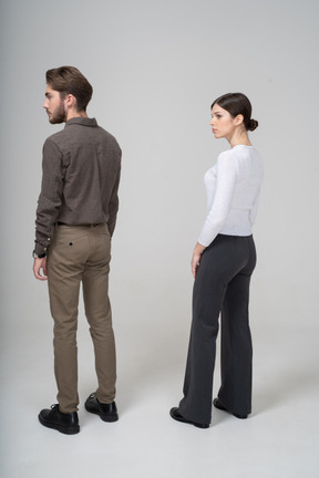Три четверти сзади молодой пары в офисной одежде, стоящей на месте