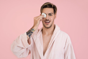 Beau mec fait sa routine de beauté et ferme un œil avec un coton