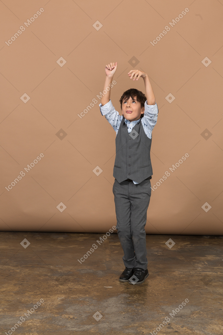 Vista frontal de un niño con traje gris bailando